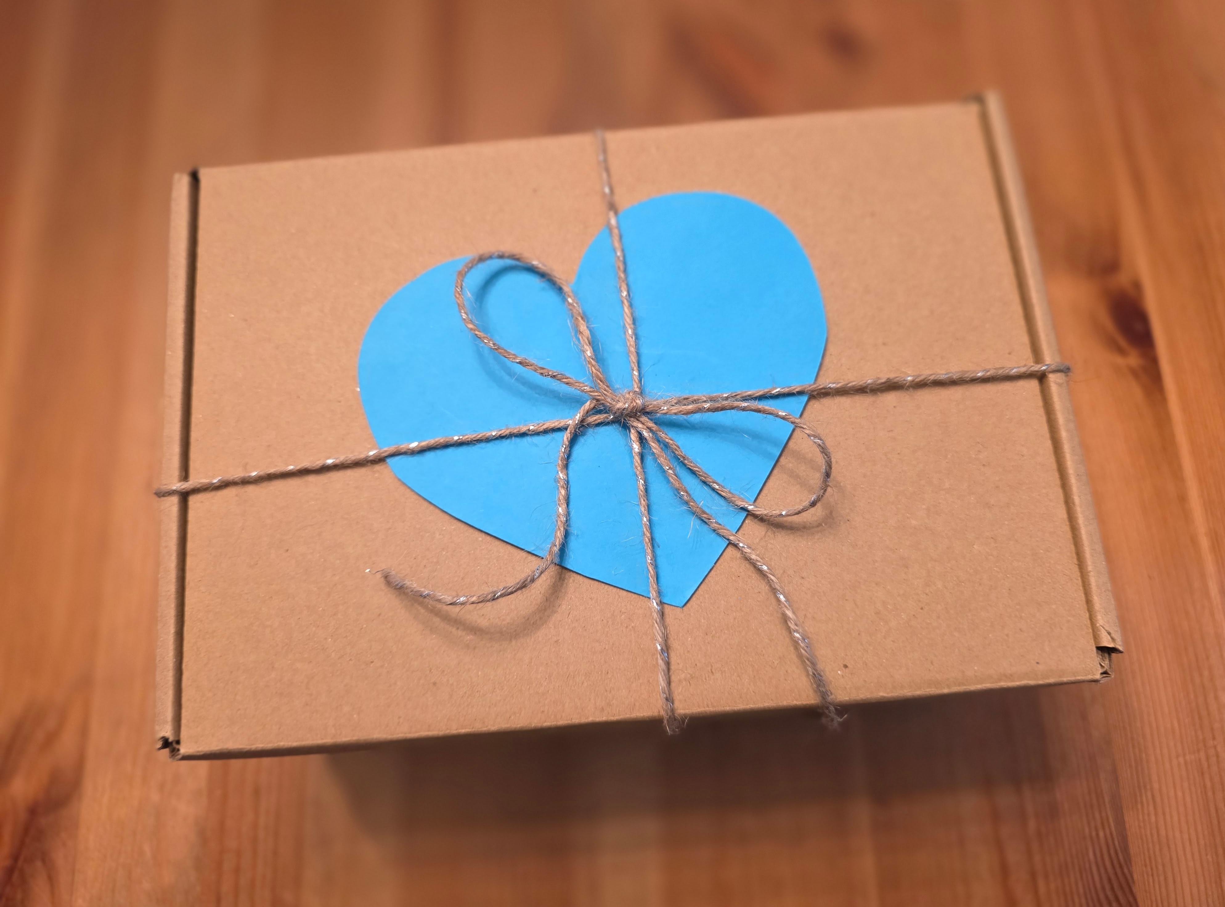 image of a box with a twine bow holding a turquoise paper heart beneath it.