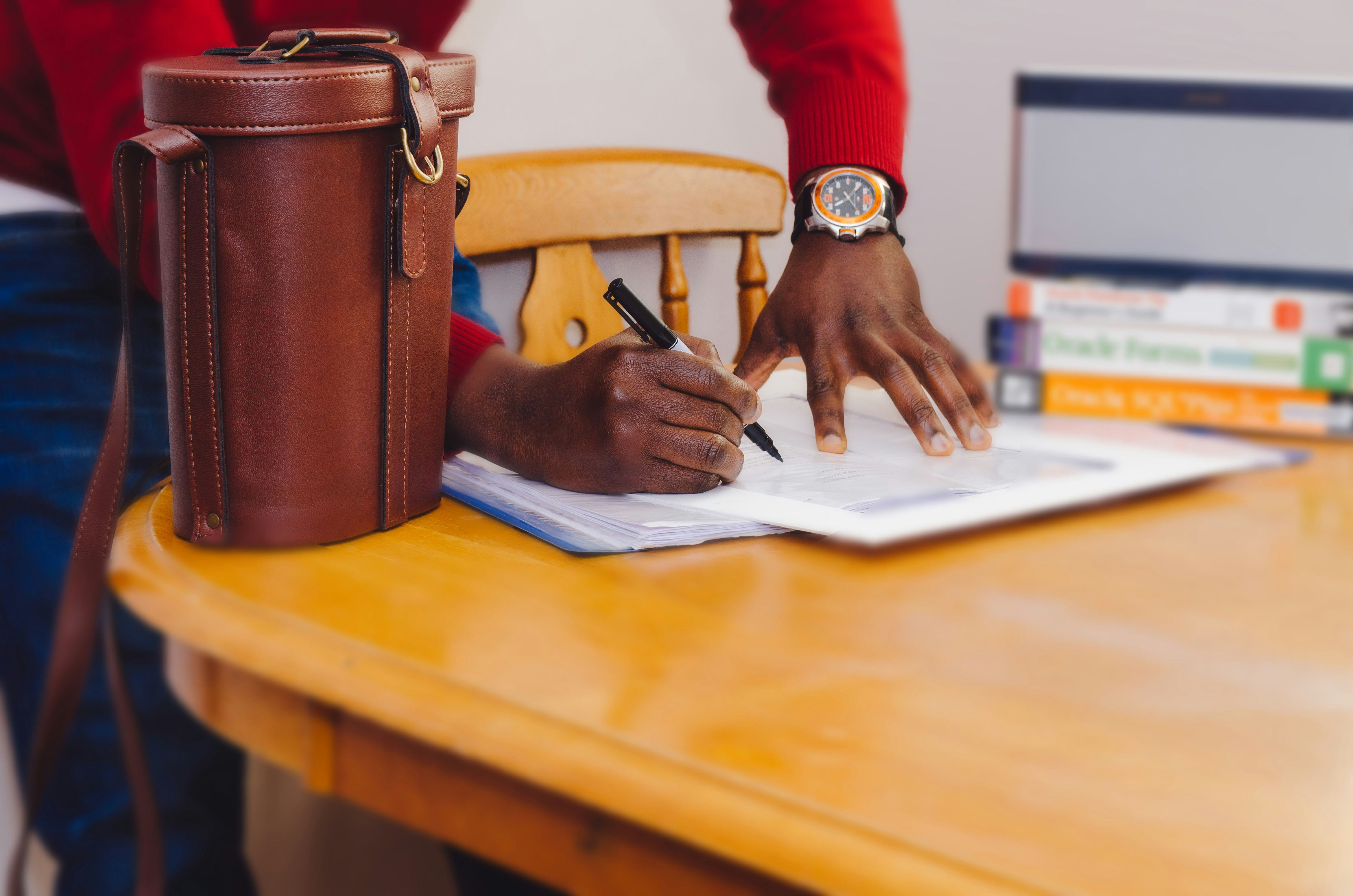 person signing forms on a wooden table