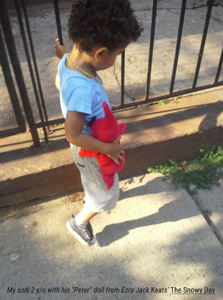 a child walking down the sidewalk holding a doll