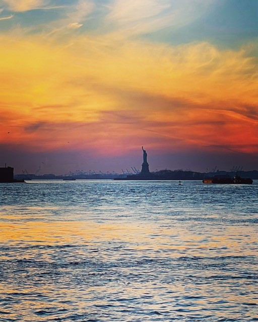 statue of liberty across the water at sunset