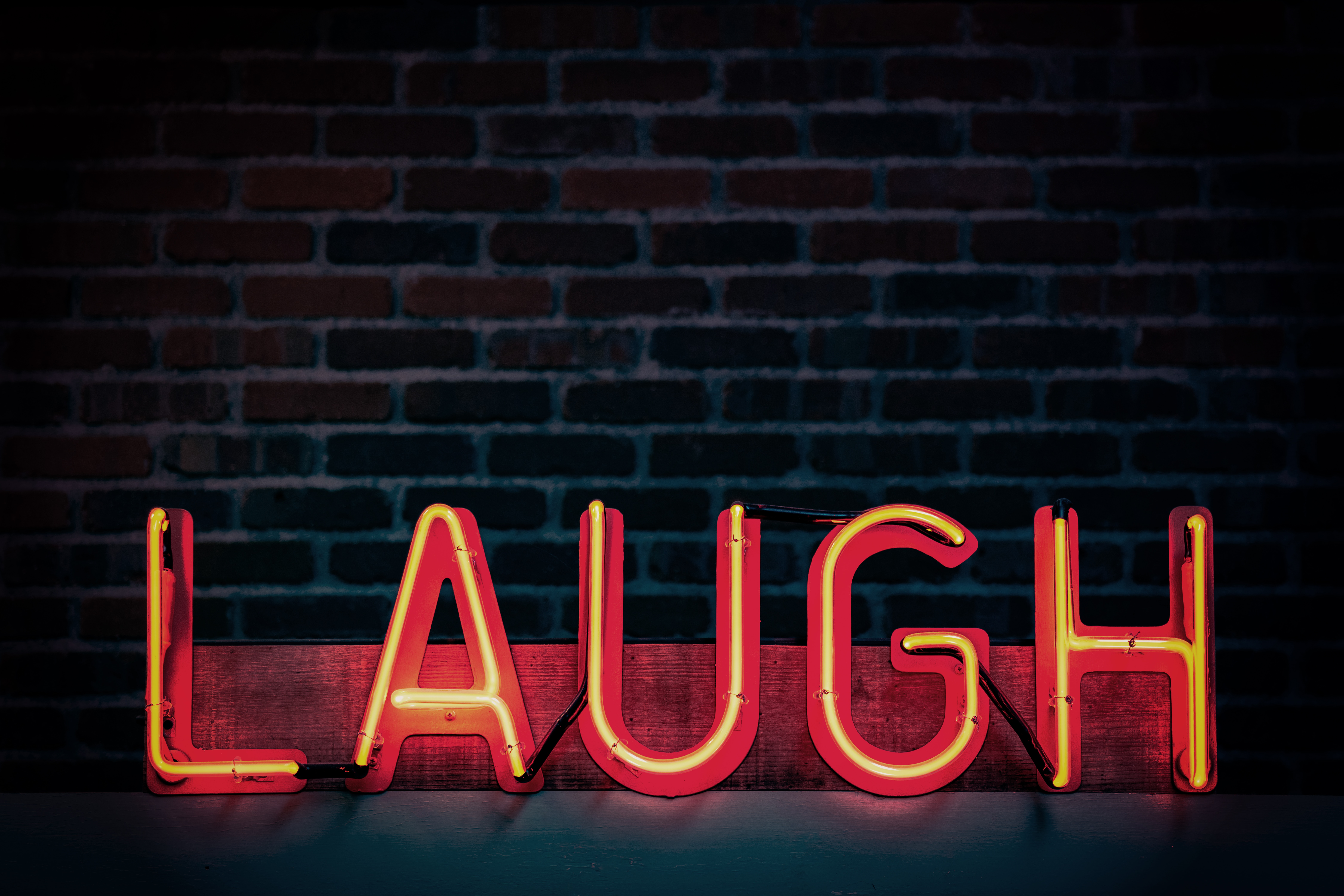 A red neon sign that says "laugh" 